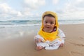 Cute baby wearing a yellow duck cartoon bathrobe sitting and playing on the beach near the sea Royalty Free Stock Photo