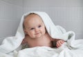 Cute baby in white bathing towel in bathroom