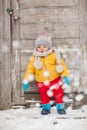 Cute baby in thermal clothes standing and playing in the snow