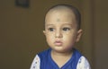 Cute bald indian baby boy in blue and white shirt looking away. Head and shoulder shot. Close up Royalty Free Stock Photo