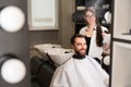 Cute barber woman in barbershop styling male hair