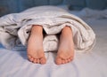 cute bare feet of a child wrapped in a blanket on the bed close-up