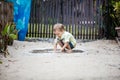 Cute barefoot boy plunging hands in puddle