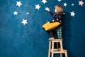 Cute barefoot little boy in pyjamas stays on wood stairs ladder with yellow soft pillow Royalty Free Stock Photo