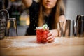 Cute barista finishes preparation of alcoholic cocktail with mint leaves of powdered sugar