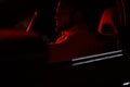 cute bearded strong rich young man in white shirt sitting in luxury sport muscle car lit with red light in night city Royalty Free Stock Photo