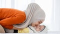 A cute and beautiful Asian Muslim in hijab dress kissing her baby daughter with a tender gesture. Love, care, and relationship Royalty Free Stock Photo