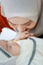 A cute and beautiful Asian Muslim in hijab dress kissing her baby daughter with a tender gesture. Love, care, and relationship Royalty Free Stock Photo