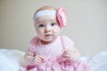 Cute beautiful baby girl sitting on a bed in pink dress Royalty Free Stock Photo