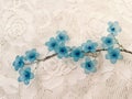 Cute beautiful blue artificial flower on the white lace background Royalty Free Stock Photo