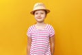 Cute beautiful charming little girl in a straw hat and a striped t-shirt on a yellow background. Closeup portrait of a child Royalty Free Stock Photo