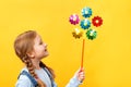 Cute beautiful child holding a pinwheel toy. Little girl close-up on a yellow background Royalty Free Stock Photo