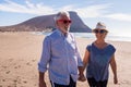 Cute and beautiful couple of seniors having fun together and enjoying their vacations at the beach walking on the sand and smiling Royalty Free Stock Photo