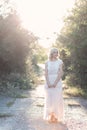 Cute beautiful girl blonde curly hair walking in the woods in a wedding dress in the sun at sunset Royalty Free Stock Photo