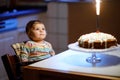 Cute beautiful little baby girl celebrating first birthday. Child blowing one candle on homemade baked cake, indoor Royalty Free Stock Photo