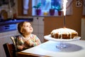 Cute beautiful little baby girl celebrating first birthday. Child blowing one candle on homemade baked cake, indoor Royalty Free Stock Photo