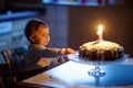 Cute beautiful little baby girl celebrating first birthday. Child blowing one candle on homemade baked cake, indoor Royalty Free Stock Photo