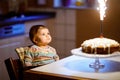Cute beautiful little baby girl celebrating first birthday. Child blowing one candle on homemade baked cake, indoor Royalty Free Stock Photo