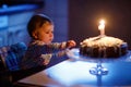 Cute beautiful little baby girl celebrating first birthday. Child blowing one candle on homemade baked cake, indoor Royalty Free Stock Photo