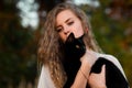 Cute,beautiful,lovely girl with black cat.Upset girl held and caress black cat outdoors in green dark forest. Royalty Free Stock Photo