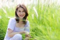 Cute beautiful middle-aged Asian woman sitting in mass green grass with sunlight shines from the back