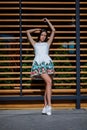 A cute, beautiful and pretty female in a trendy white dress on the street. The woman is posing on the wooden background. Royalty Free Stock Photo