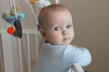 Beautiful Sad European baby stands in a white canopy bed and turns to the camera. Royalty Free Stock Photo