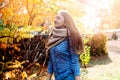 Cute beautiful smile woman walking in red autumn park. Girl in knitten scarf near tree and she is happy Royalty Free Stock Photo