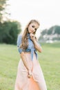 Cute beautiful sweet girl in a denim shirt and pink chiffon skirt smiles mysteriously