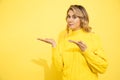 Cute beautiful woman wearing yellow sweater standing over yellow isolated background with convincing face, pointing with hands to