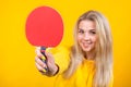 Cute beautiful young blonde woman in casual yellow sporty clothes play ping pong, holding a ball and racquet Royalty Free Stock Photo