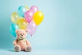 Cute beige fluffy bear kid toy with colourful birthday balloon bunch on minimal pastel background