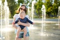 Cute big sister holding her baby brother by city fountain. Adorable teenage girl playing with her baby boy brother. Children Royalty Free Stock Photo