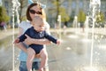 Cute big sister holding her baby brother by city fountain. Adorable teenage girl playing with her baby boy brother. Children Royalty Free Stock Photo