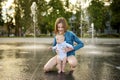 Cute big sister holding her baby brother by city fountain. Adorable teenage girl playing with her baby boy brother. Children Royalty Free Stock Photo