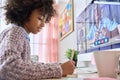 Cute black preteen schoolgirl sitting learning at home, watching video class. Royalty Free Stock Photo