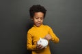 Cute black child putting in piggy bank euro coin