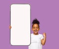 Cute black girl preschooler showing smartphone, mockup