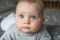 cute blond baby with big blue eyes, baby is laying on bed and looking at camera, closeup portrait of face Royalty Free Stock Photo