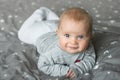 Cute blond baby with blue eyes is laying on grey bed view from above Royalty Free Stock Photo