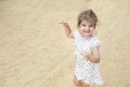 Cute blond baby girl in beautiful dress walking on a long sandy beach Royalty Free Stock Photo