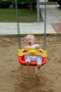 Cute blond baby girl sitting in a swing Royalty Free Stock Photo