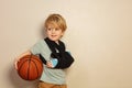 Cute blond boy with broken hand holding basketball ball Royalty Free Stock Photo