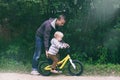 Cute blond boy learning to ride bicycle. Father teaching his little child to ride bike in spring summer park. Happy family moments Royalty Free Stock Photo