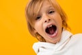 Cute blond boy screams on a yellow studio background close-up Royalty Free Stock Photo