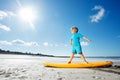 Side portrait of a blond boy stand on the surfboard at beach Royalty Free Stock Photo