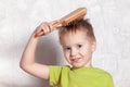 Cute blond caucasian baby boy brushing his hair, smiling. Royalty Free Stock Photo