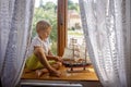 Cute blond child, boy, playing at home with big ship on the window Royalty Free Stock Photo