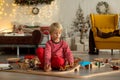 Cute blond child in pajama, playing at home on Christmas day with trains and railroad Royalty Free Stock Photo