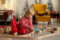 Cute blond child in pajama, playing at home on Christmas day with trains and railroad Royalty Free Stock Photo